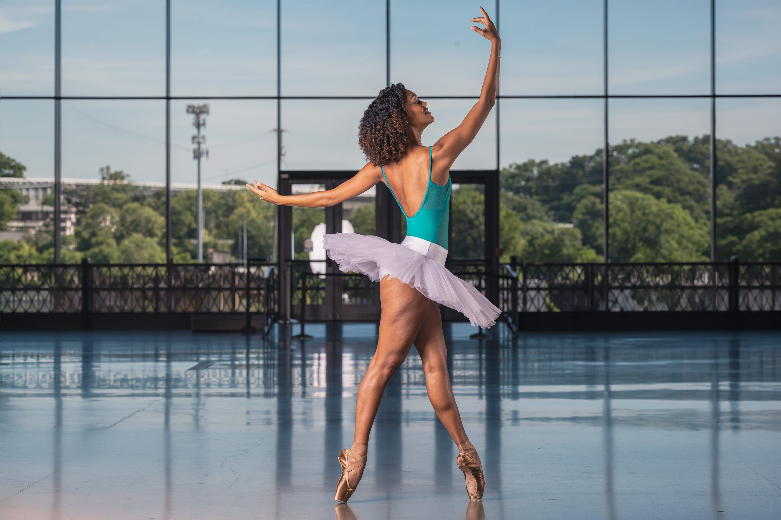 Ballet dancer en pointe in a tutu on a reflective glass-walled terrace