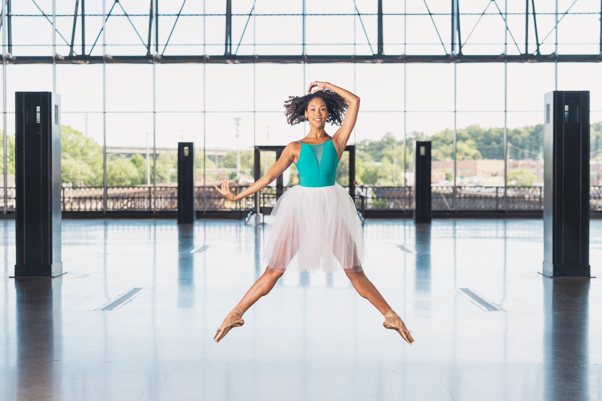 Ballet dancer leaping in a sunlit glass pavilion in Richmond